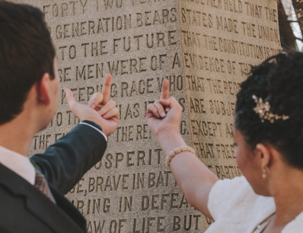 A bride and groom flash their middle fingers at a confederate memorial. Amanda and Steve Say Fuck the Confederacy - Photo by Amanda Summerlin Photgraphy