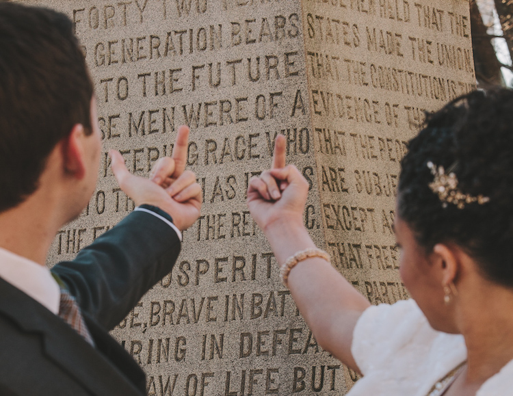 A bride and groom flash their middle fingers at a confederate memorial. Amanda and Steve Say Fuck the Confederacy - Photo by Amanda Summerlin Photgraphy