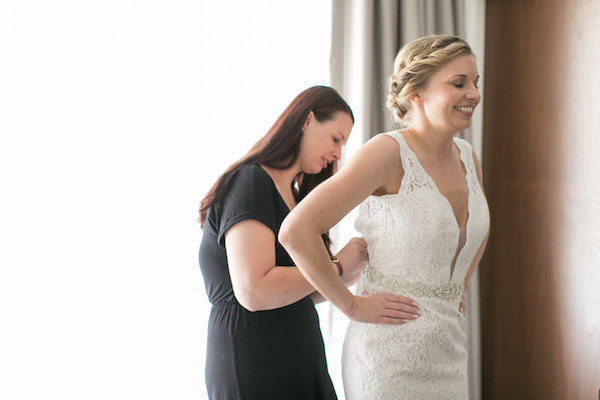 Aisle Less Traveled associate coordinator Kelly zips Kiley into her wedding gown. Photo: Christy Tyler Photography