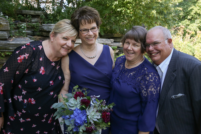 A woman in a floral dress stands with Mary, in a navy dress; Pam, in a navy blouse; and a man in a suit at Chicago's Lily Pond