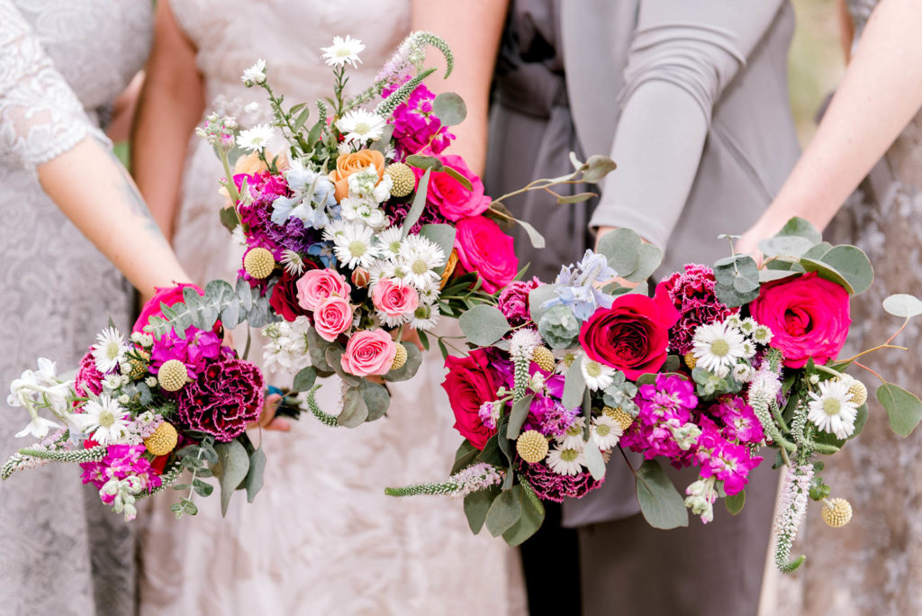 Bride and Wedding Party hold out colorful flower bouquets