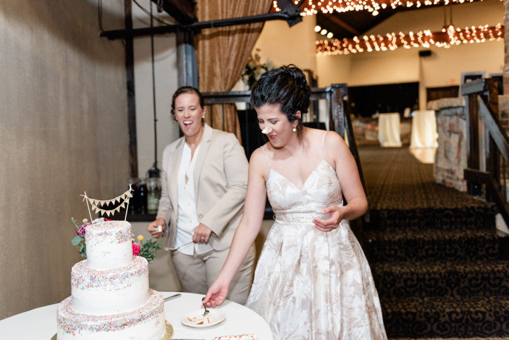 Brides smear wedding cake on each others faces