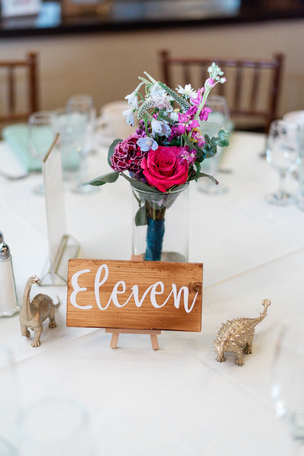 DIY wedding centerpiece colorful flowers wood painted table number gold painted dinosaurs