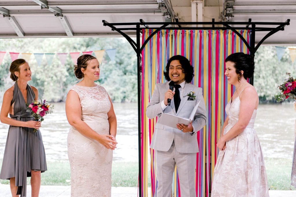 Two Brides during wedding ceremony with colorful ribbon wall backdrop