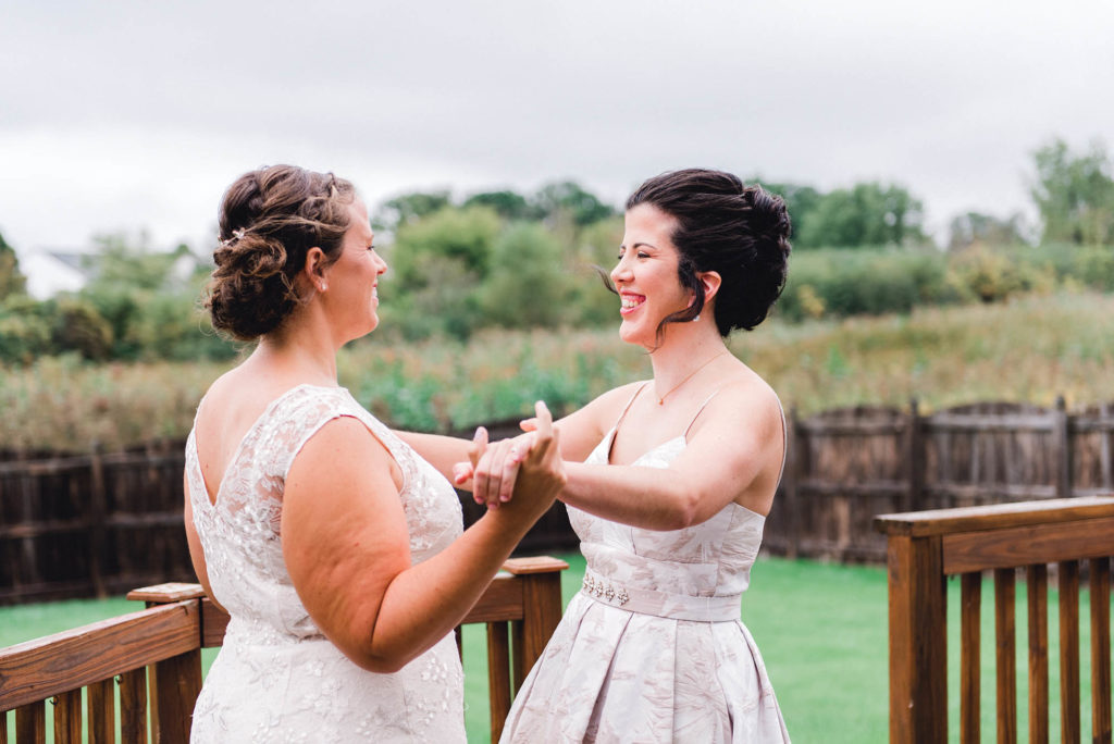 Two brides holding hands and laughing