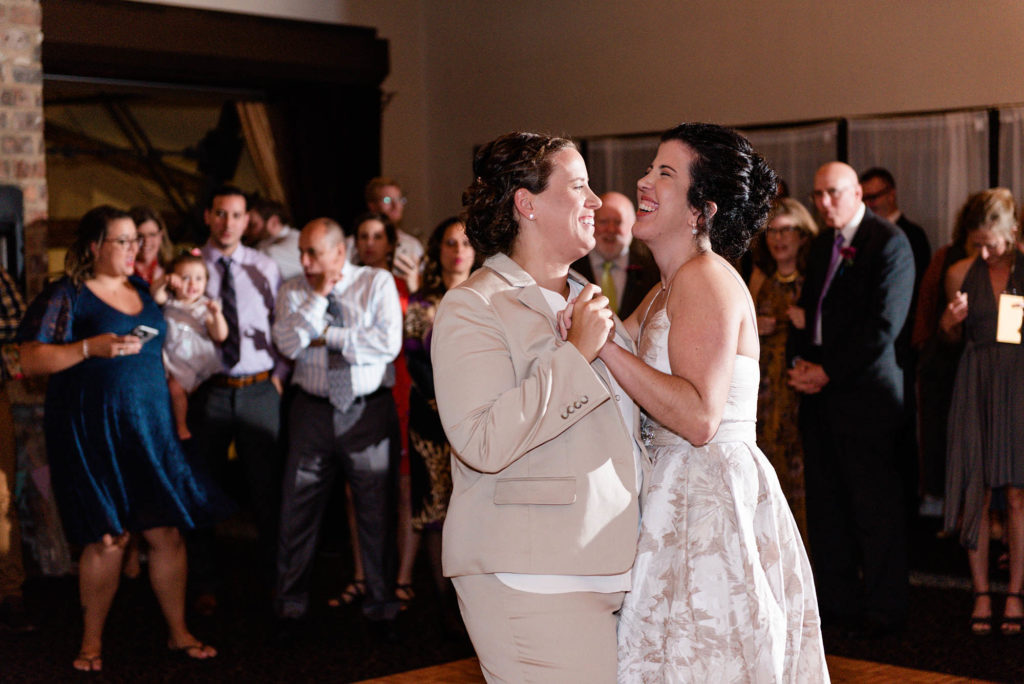Two brides laughing and smiling during first dance
