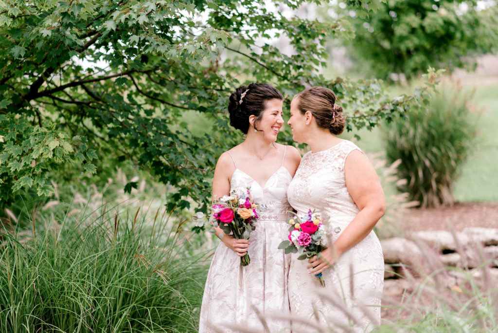 Two brides smiling at each other