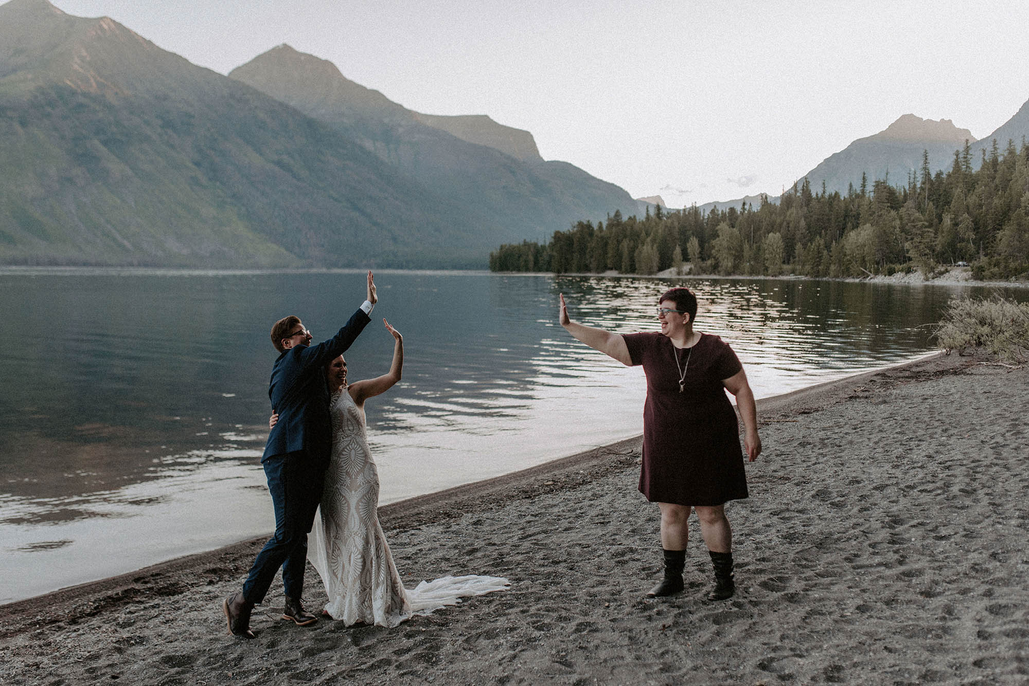 socially distant high five with two brides and wedding officiant