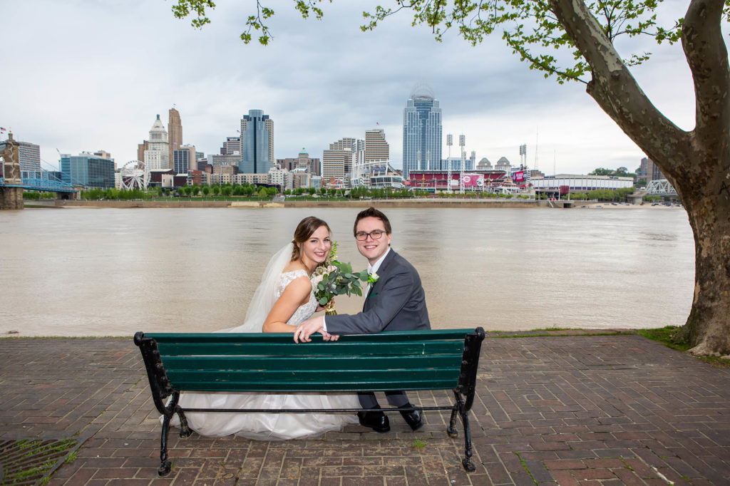 bride and groom at bench overlooking Cincinnati skyline