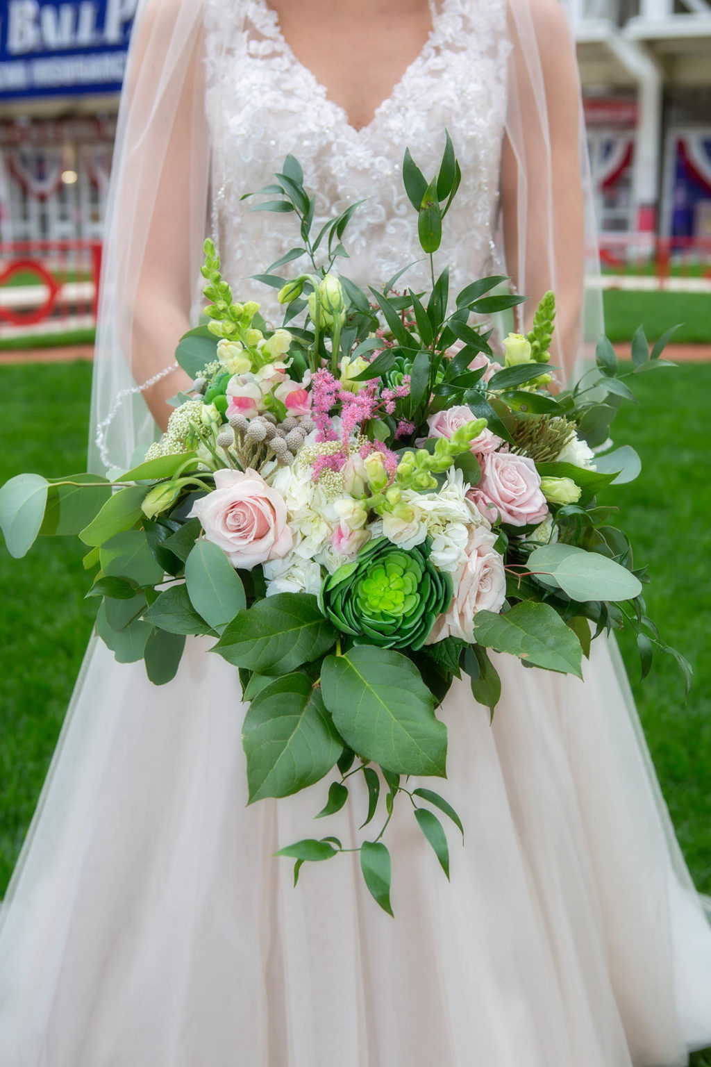 bride holding bouquet with pink and green flowers