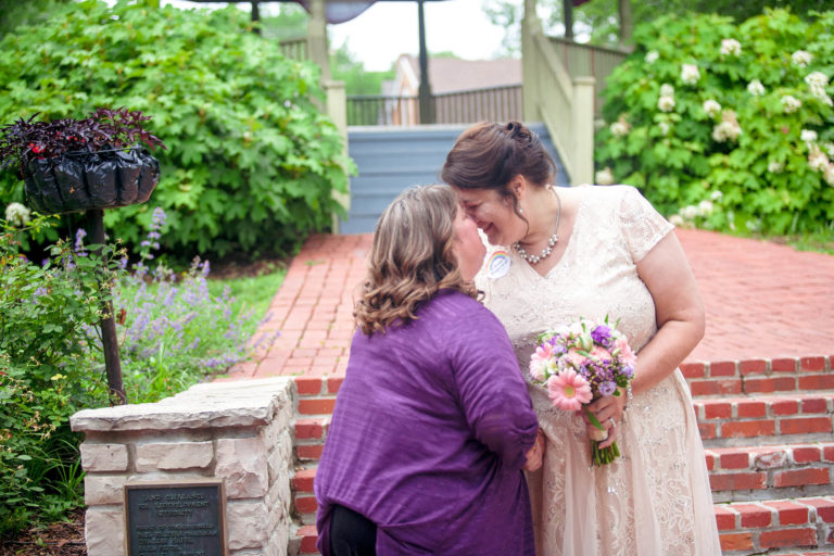 two brides touch foreheads after wedding ceremony