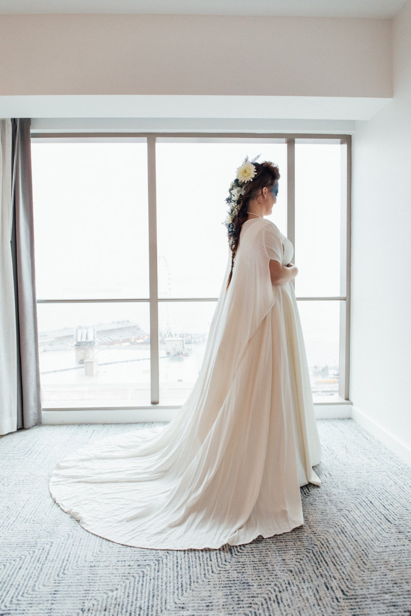 bride in white gown with dramatic cape and intricate hairstyle with flowers in her hair