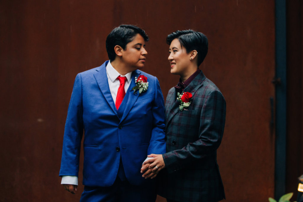 newlyweds wearing suits gaze into each others eyes