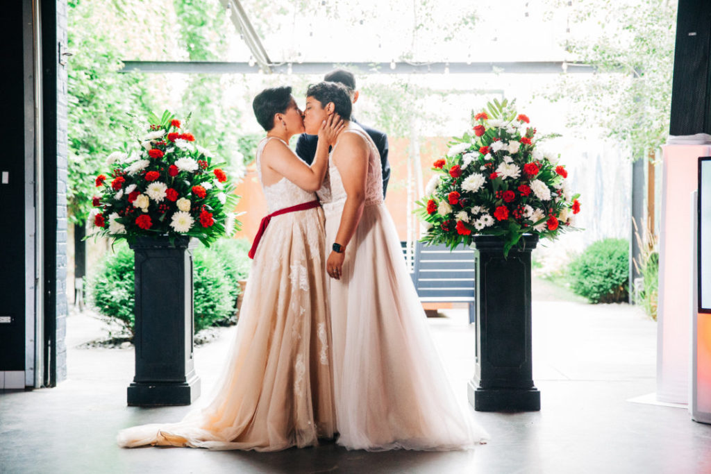 two brides kiss at wedding ceremony