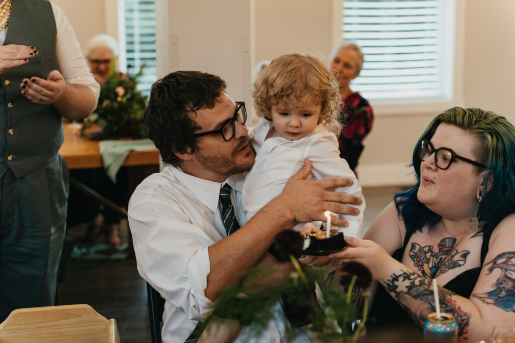 child about to blow out candle on piece of birthday wedding cake