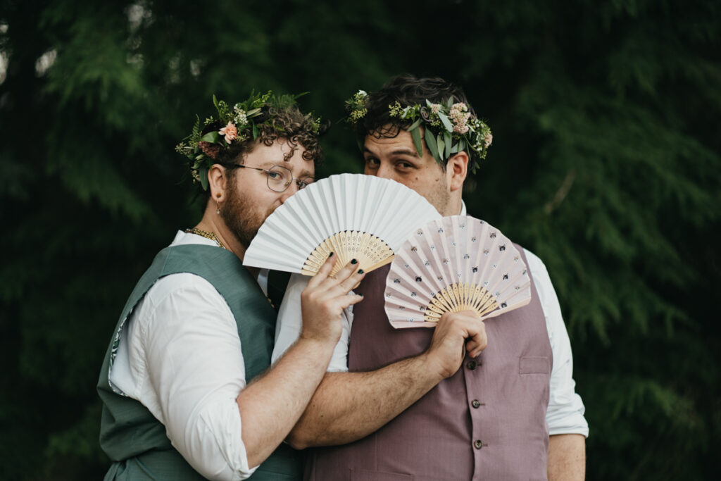 grooms holding paper fans in front of their faces