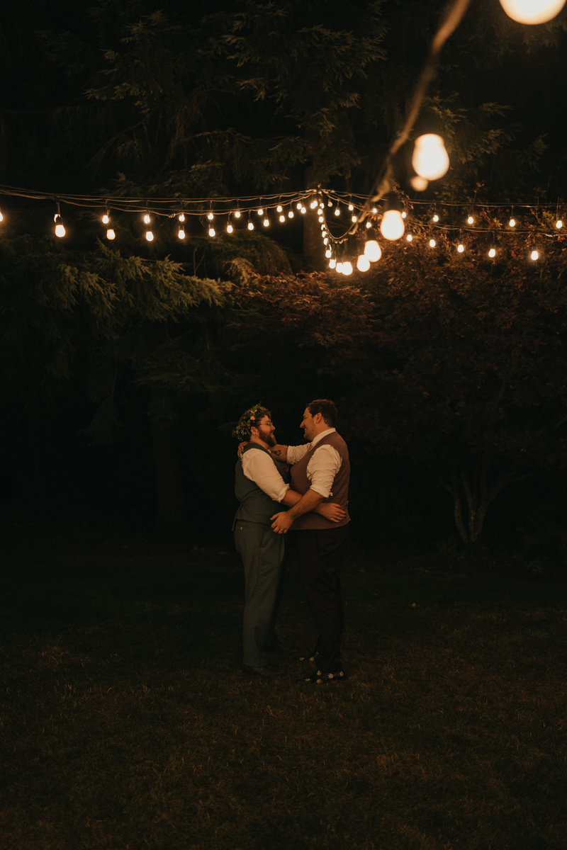 two grooms dance outside under market lights at Trinity Tree Farm wedding