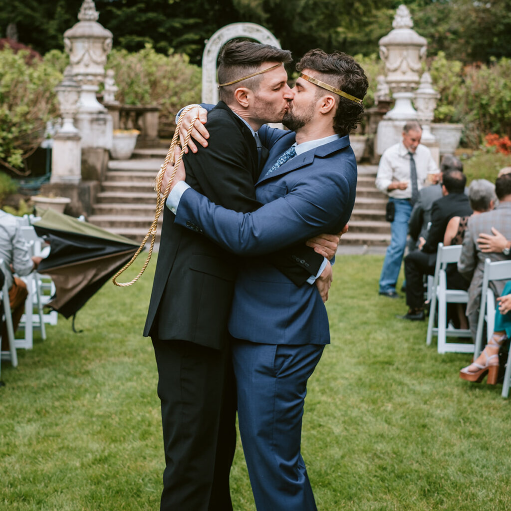 two grooms kiss at Thornewood Castle wedding ceremony
