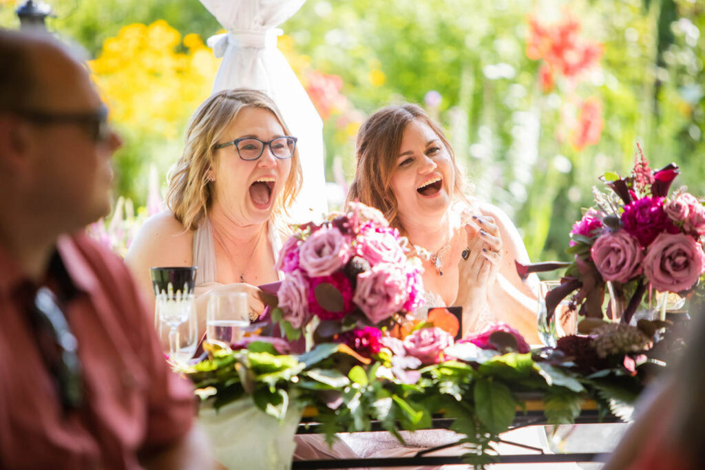 brides laughing at wedding reception table