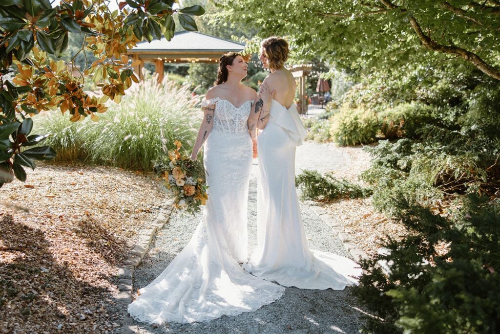 Two brides pose in the gardens at Willows Lodge wedding venue.